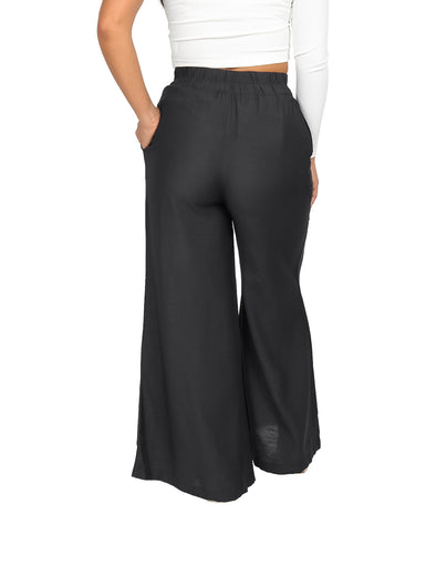 Mujer vistiendo un pantalón ancho de color negro con cintura elástica y calzado beige.