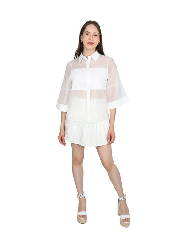 Mujer vistiendo blusa de organza blanca con mangas kimono y cuello camisero.