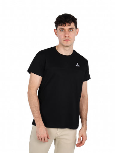Hombre vistiendo una camiseta básica de manga corta color negro con un pequeño logo blanco en el pecho.