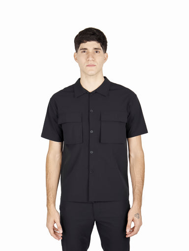 Hombre vistiendo camisa ATOK de manga corta color negro con dos bolsillos frontales y estilo outdoor.
