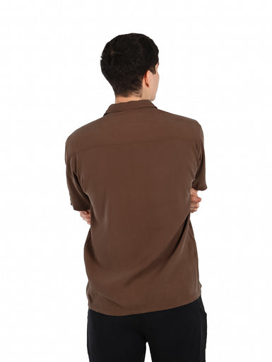 Hombre vistiendo una camisa básica de manga corta en color café con cuello abierto y botones.
