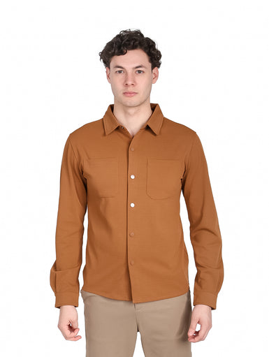 Hombre vistiendo camisa casual de color café con manga larga y dos bolsillos frontales.