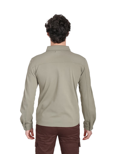 Hombre vistiendo una camisa casual de color verde con manga larga y dos bolsillos frontales.