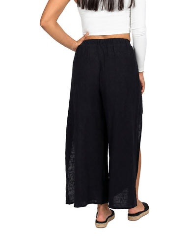 Mujer vistiendo pantalón negro de pierna ancha con abertura lateral y cintura ajustable.