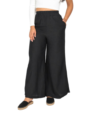 Mujer vistiendo un pantalón ancho de color negro con cintura elástica y calzado beige.