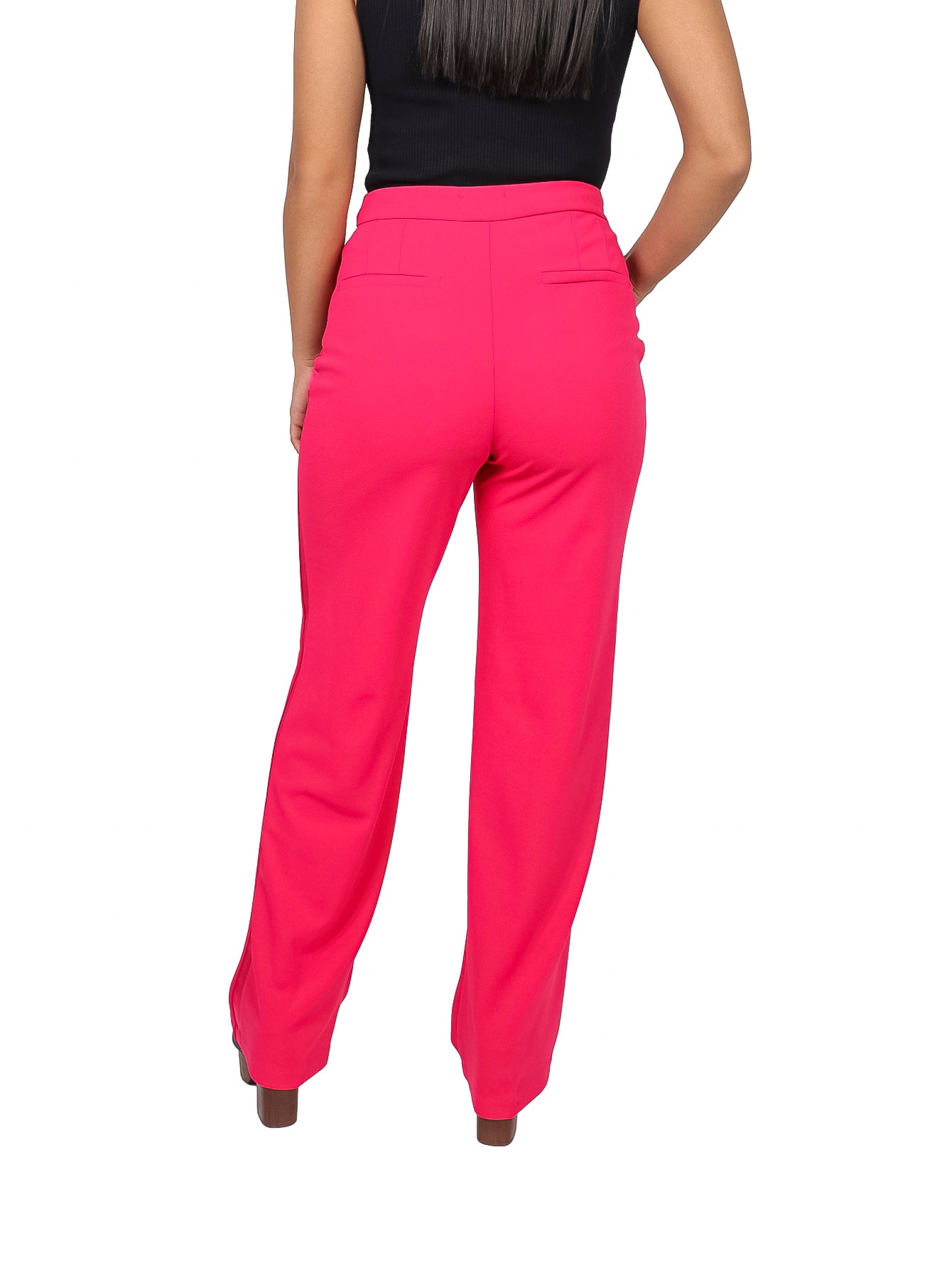 Mujer vistiendo un pantalón ancho de color fucsia con talle alto y bolsillos laterales.