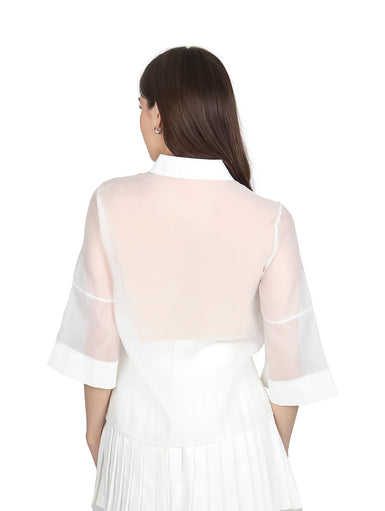 Mujer vistiendo blusa de organza blanca con mangas kimono y cuello camisero.