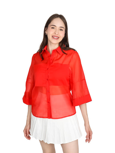 Mujer vistiendo blusa de organza roja con manga kimono y cuello, combinada con falda blanca plisada.
