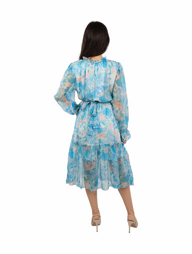 Mujer vistiendo un vestido midi de gasa color azul con estampado floral, mangas largas y cintura elástica.