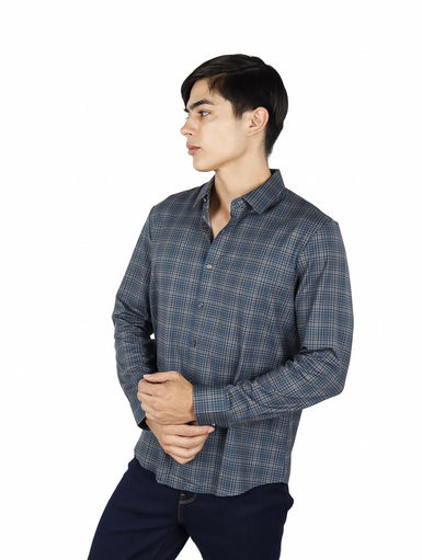 Hombre vistiendo una camisa casual de manga larga con estampado de cuadros en tonos verde y azul.
