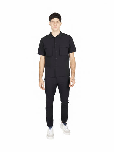 Hombre vistiendo camisa ATOK de manga corta color negro con dos bolsillos frontales y estilo outdoor.