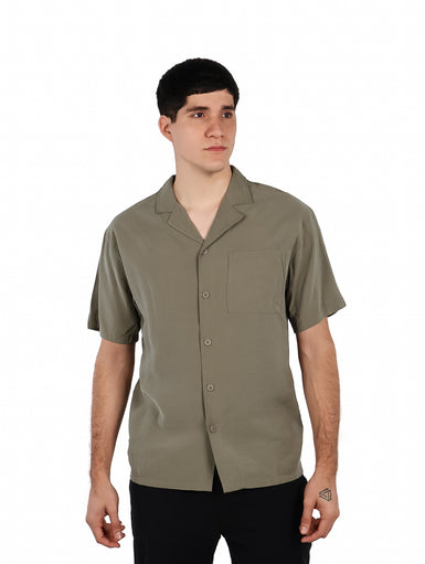 Hombre vistiendo una camisa básica de manga corta en color verde militar con cuello abierto y un bolsillo frontal.