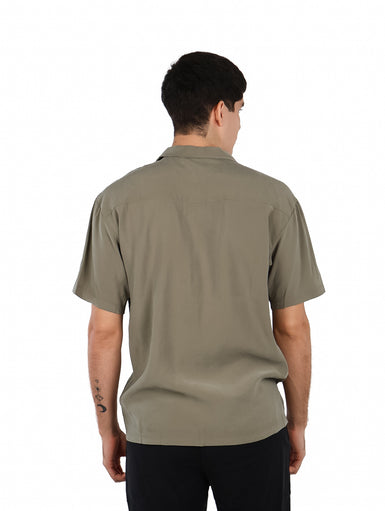 Hombre vistiendo una camisa básica de manga corta en color verde militar con cuello abierto y un bolsillo frontal.