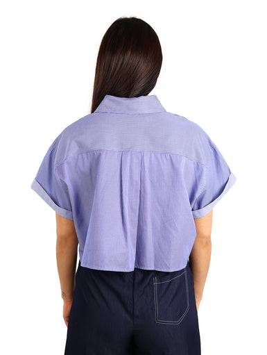 Mujer vistiendo una camisa corta de color azul oscuro con rayas finas y mangas cortas dobladas.
