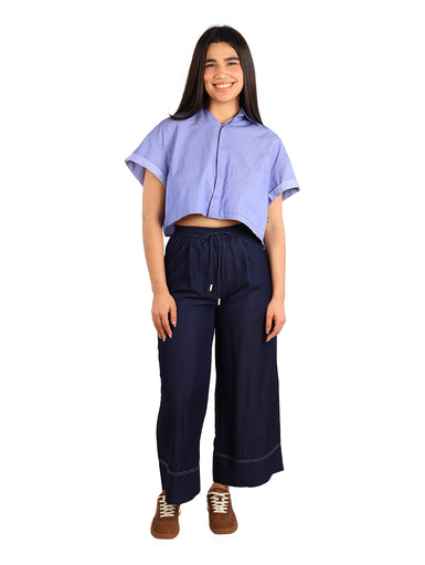 Mujer vistiendo una camisa corta de color azul oscuro con rayas finas y mangas cortas dobladas.