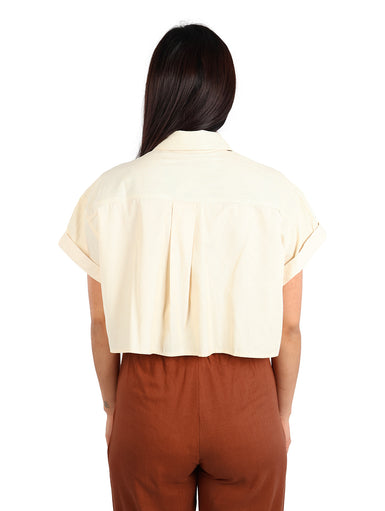 Mujer vistiendo una camisa corta color apricot con rayas finas y manga corta.