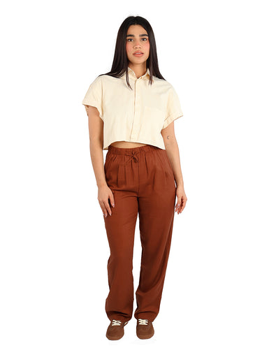 Mujer vistiendo una camisa corta color apricot con rayas finas y manga corta.