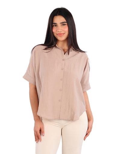 Mujer vistiendo una camisa de manga corta color khaki con botones frontales y pantalones claros.