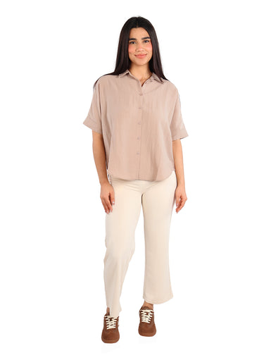 Mujer vistiendo una camisa de manga corta color khaki con botones frontales y pantalones claros.