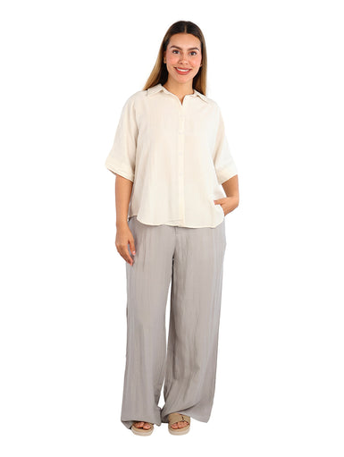 Mujer vistiendo una camisa de color linen con manga corta y botones frontales, estilo casual.