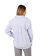 Mujer vistiendo camisa de maternidad azul oscuro con rayas blancas, manga larga y botones frontales.
