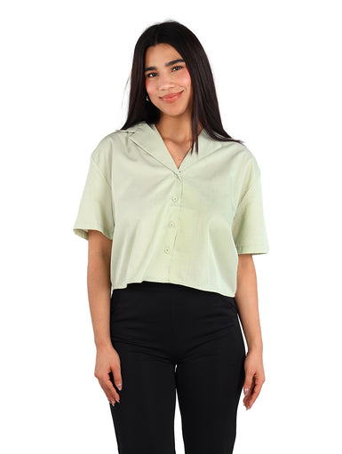 Mujer vistiendo una camisa de manga corta color verde claro con botones y cuello abierto.
